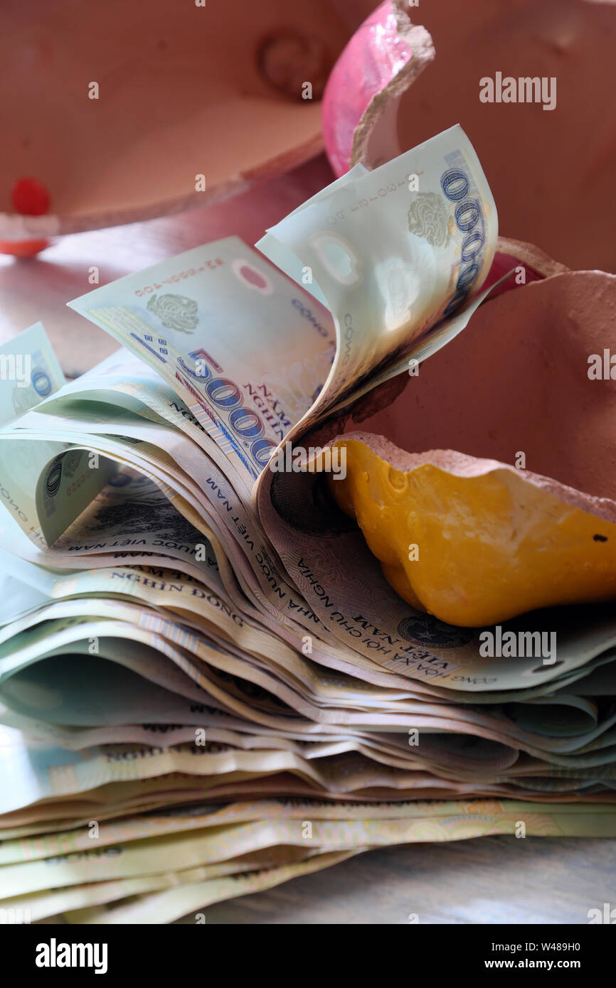 Risparmio di denaro da rotture di salvadanaio per salvare fino per la situazione di emergenza o di previdenza o comprare casa, molti Dong vietnamita banconota Foto Stock