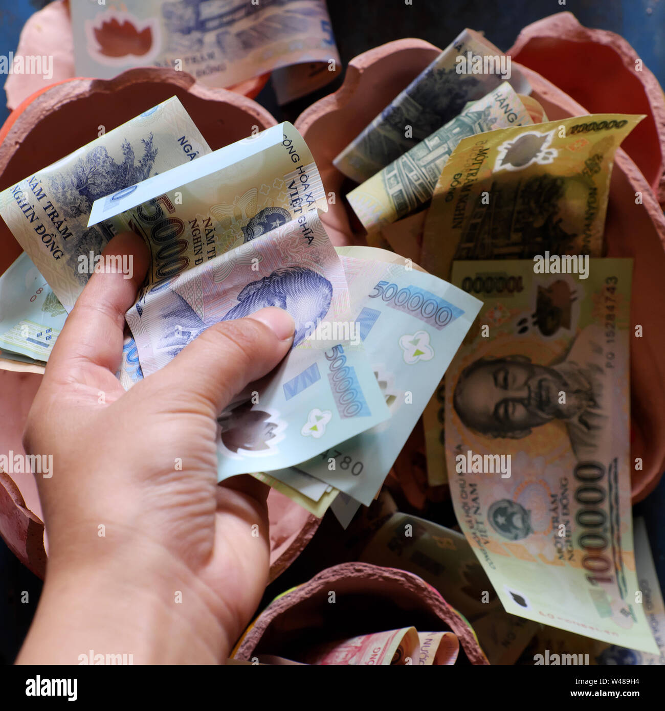 Risparmio di denaro da rotture di salvadanaio per salvare fino per la situazione di emergenza o di previdenza o comprare casa, molti Dong vietnamita banconota Foto Stock