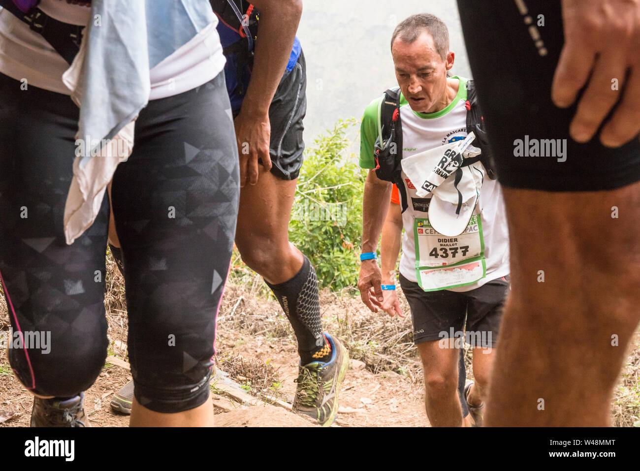 Stanco delle guide di scorrimento nel sensore pioggia, arrampicata al di fuori di un cratere sulla ripida traccia approssimativa da les deux Bras nel Cirque de Mafate durante il Grand Raid, Reunion Foto Stock