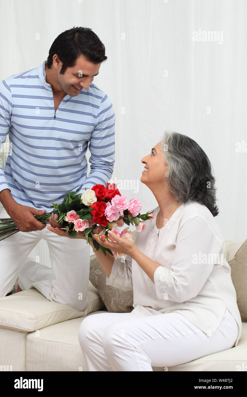 Uomo che dà mazzo di fiori a sua madre Foto Stock