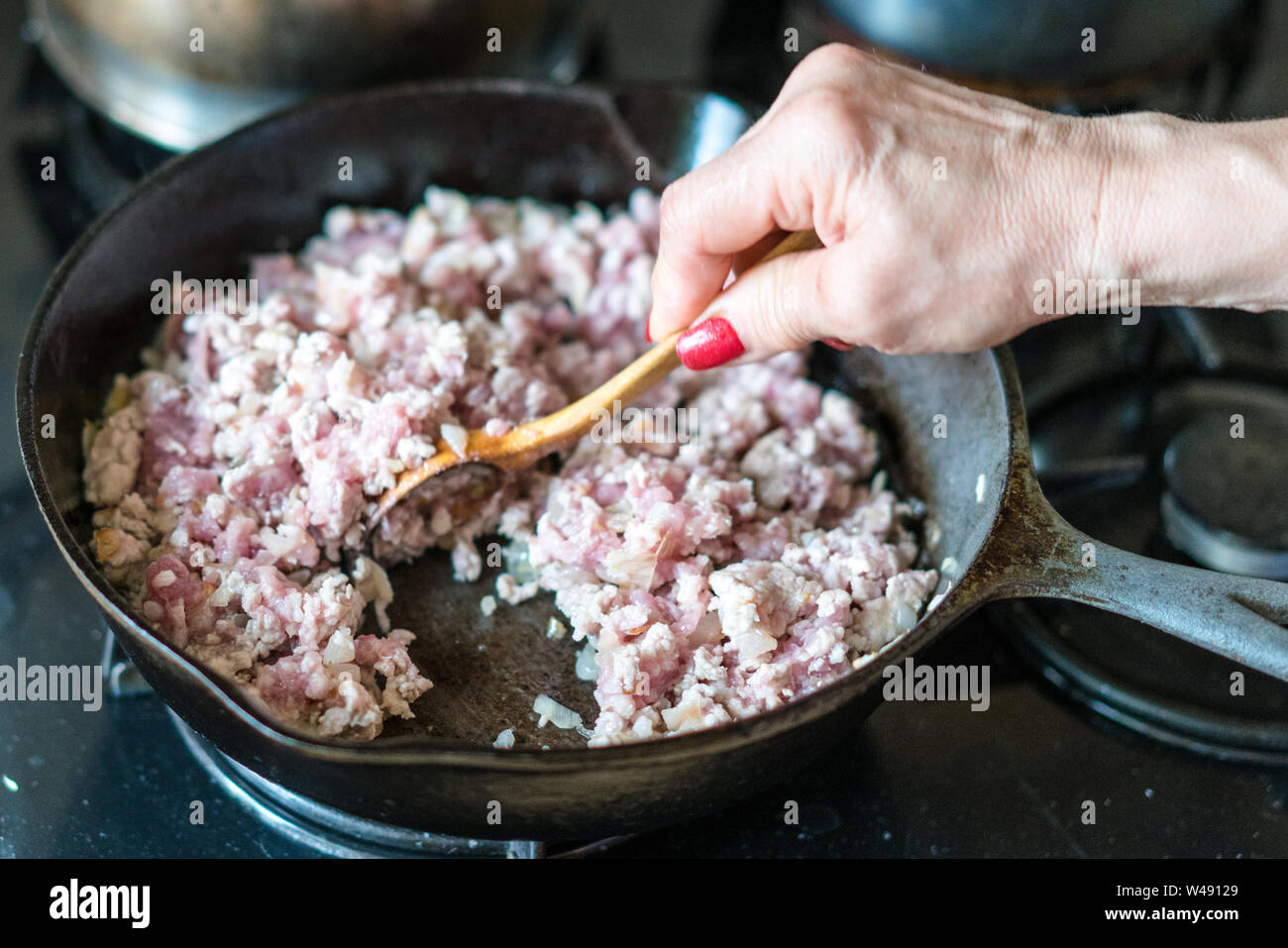 Donna agitazione la carne macinata di maiale arrostito su una padella Foto Stock