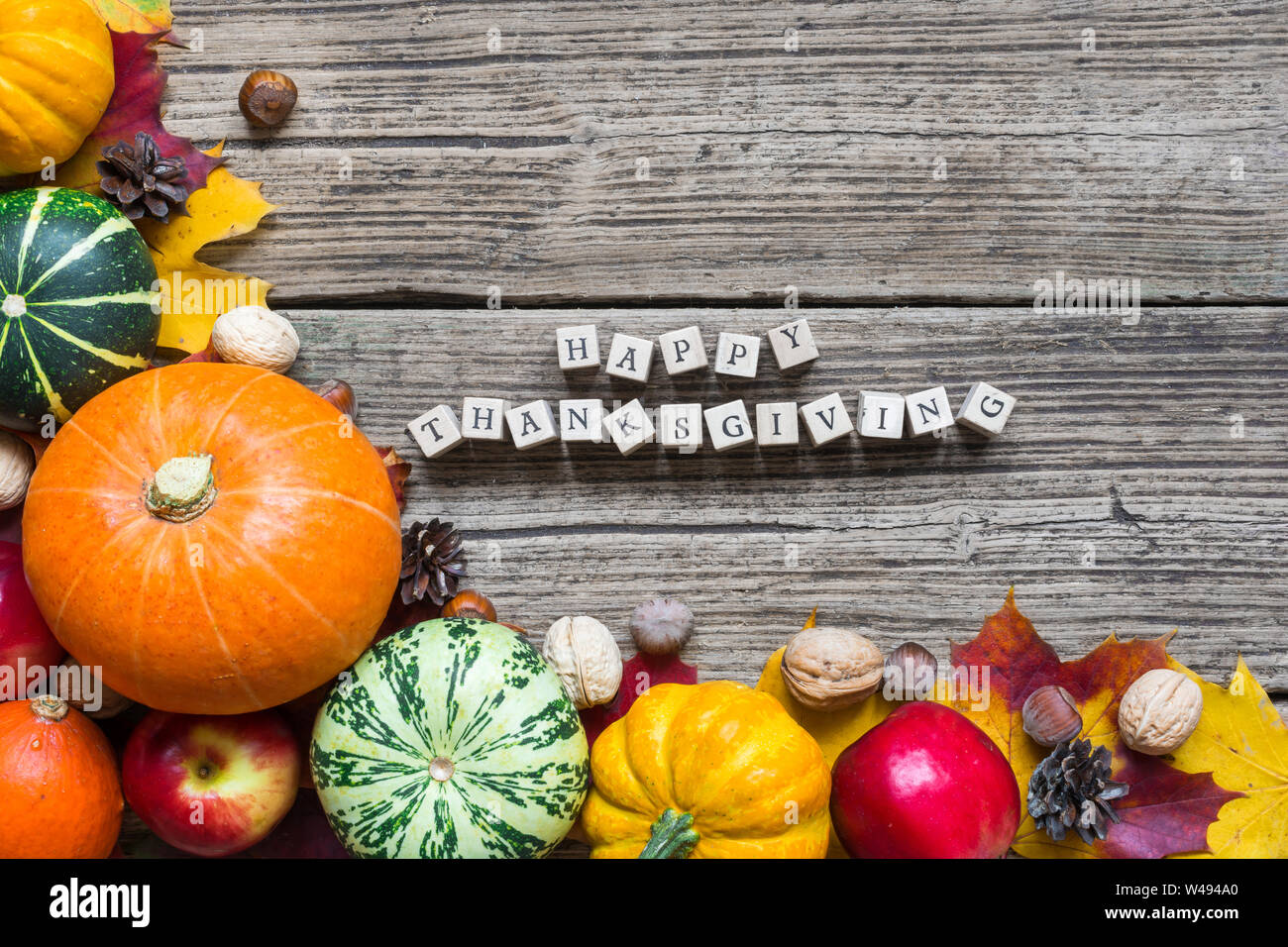 Felice ringraziamento iscrizione con caduta di frutta e verdura con foglie di acero sul tavolo di legno. Sfondo di ringraziamento Foto Stock