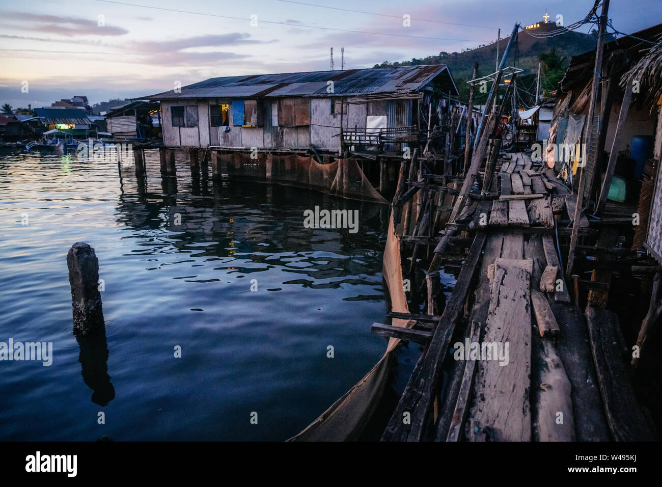 Quartiere povero baraccopoli con case in legno in prossimità di acqua al tramonto, Coron city, PALAWAN FILIPPINE Foto Stock