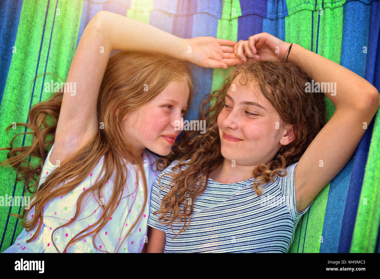 Felici sono amici di ridere su una amaca in una calda giornata di sole Foto Stock