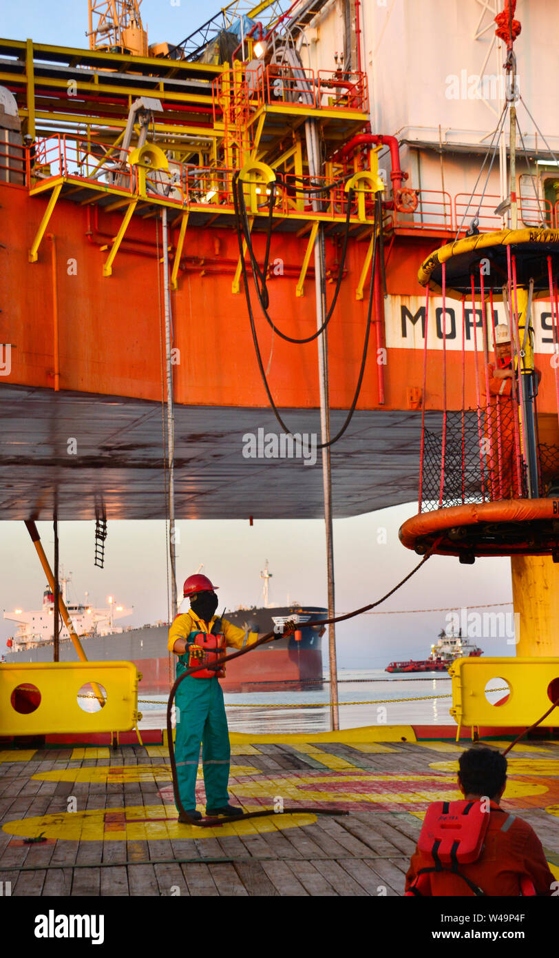 La nave l'equipaggio lavorano sul ponte durante il trasferimento piattaforma petrolifera personali per nave dal cesto di sicurezza operano tramite il gruista Foto Stock