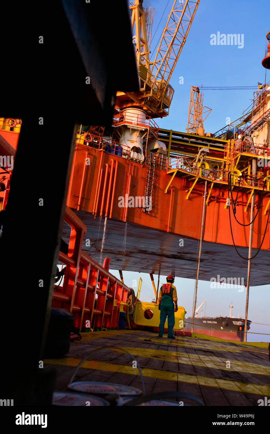 La nave l'equipaggio lavorano sul ponte durante il trasferimento piattaforma petrolifera personali per nave dal cesto di sicurezza operano tramite il gruista Foto Stock