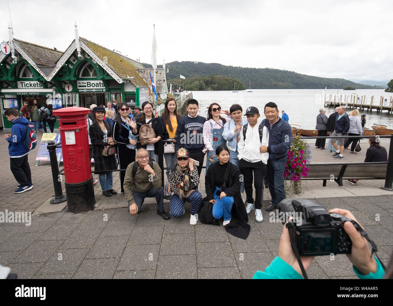 Lago di Windermere Cumbria Regno Unito 21 luglio 2019 UK Meteo .Nuvoloso Giorno a Bowness Bay sul Lago di Windermere ,turisti cinesi di alimentazione e in posa con la locale cigni credito Shoosmith Gordon/Alamy News live Foto Stock