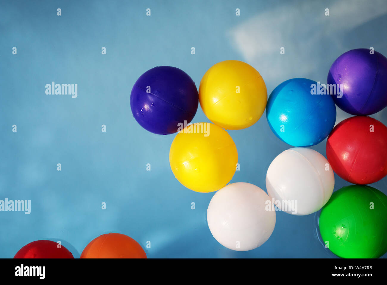 Plastica sfere colorate nella piscina per bambini sullo sfondo di acqua blu Foto Stock