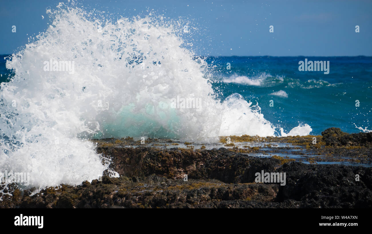 Un ondata di schiantarsi contro una roccia affiorante su Oahu Hawaii's south shore. Foto Stock