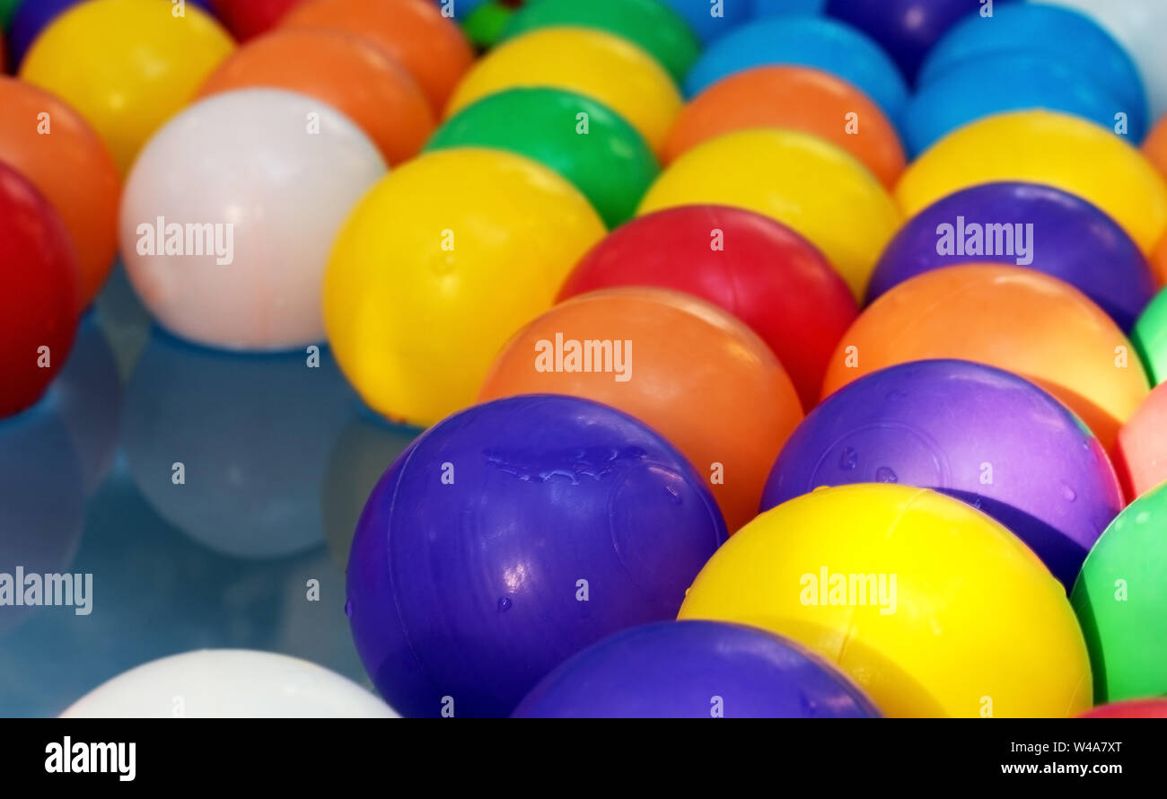 Lastic palle colorate nella piscina per bambini sullo sfondo di acqua blu Foto Stock
