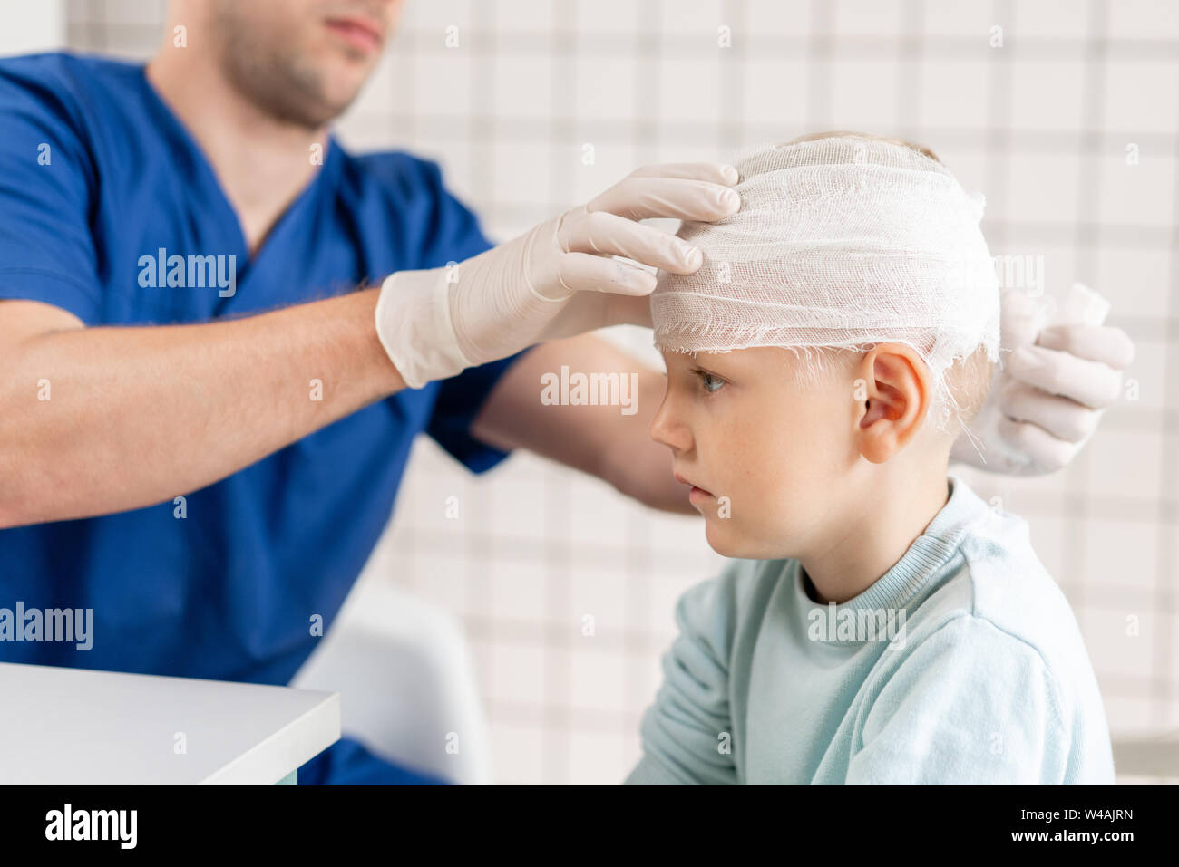 Medico bendato un ragazzo testa con trauma nella sua testa e bendato elastico intorno alla sua testa Foto Stock