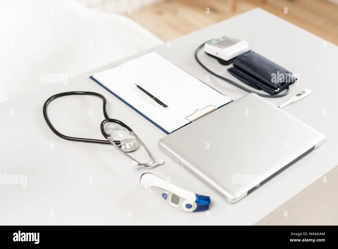 Stetoscopio, la misura della pressione del sangue e il laptop sulla scrivania in legno per l'analisi dei risultati medici. Foto Stock