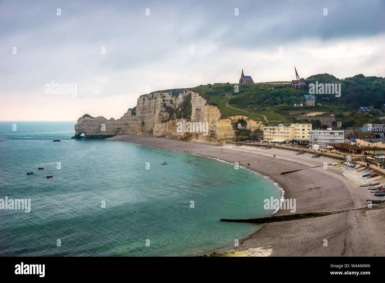 Scenario paesaggistico di Etretat, spiaggia, il lungomare e la Falaise d'Amont, iconico scogliera della costa normanna, al tramonto, Francia. Foto Stock