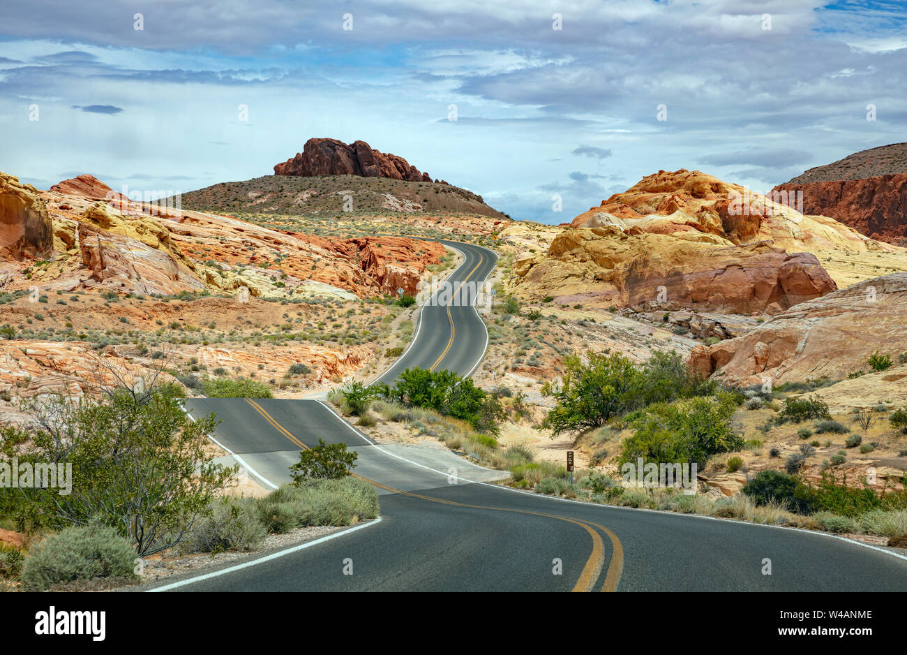 La valle del fuoco autostrada Nevada, USA. Svuotare Winding Road passando attraverso il deserto americano e valle rocce rosse, blu cielo nuvoloso sfondo Foto Stock