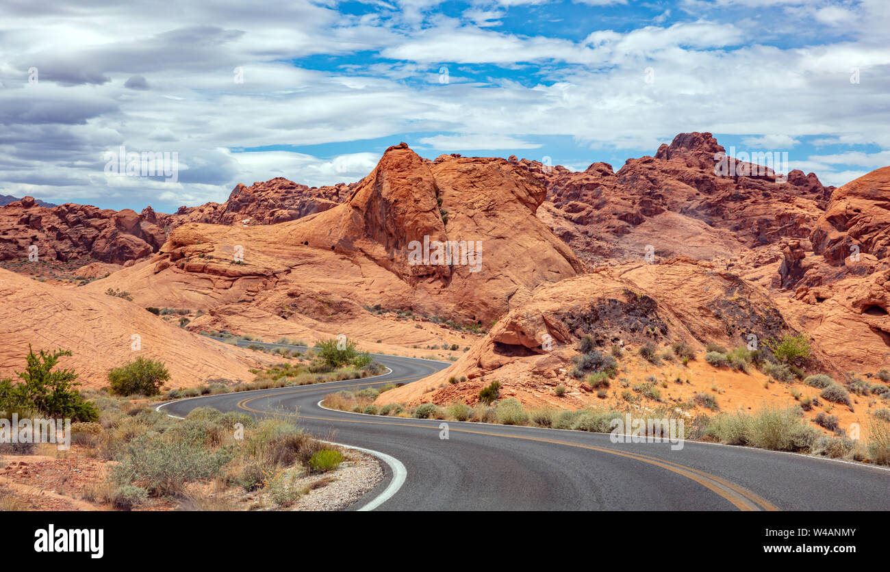 La valle del fuoco autostrada Nevada, USA. Svuotare Winding Road passando attraverso il deserto americano e valle rocce rosse, blu cielo nuvoloso sfondo Foto Stock