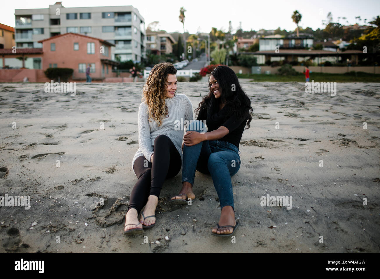 Passo la mamma e figlia passo il sorriso a un altro sulla spiaggia al tramonto Foto Stock