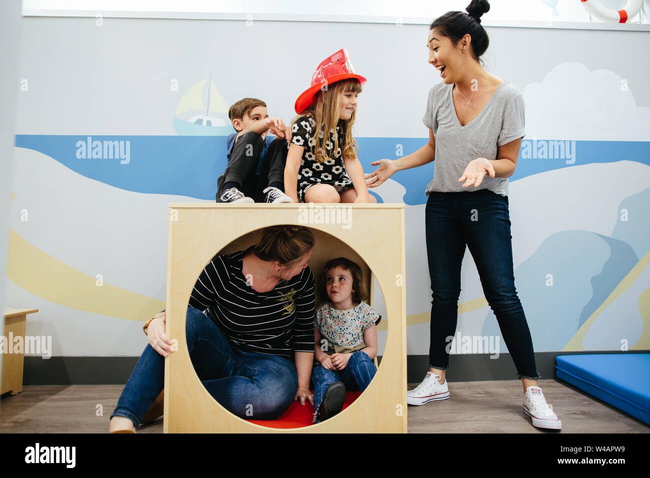 Gli insegnanti interagiscono con i bambini in un cubo di struttura di gioco Foto Stock
