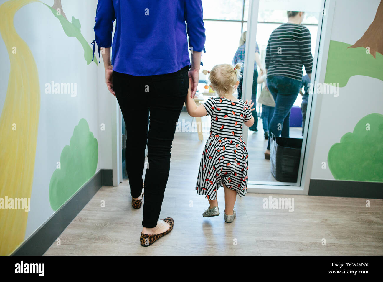 Il Toddler ragazza madre e tenere le mani mentre si cammina in una stanza a scuola Foto Stock