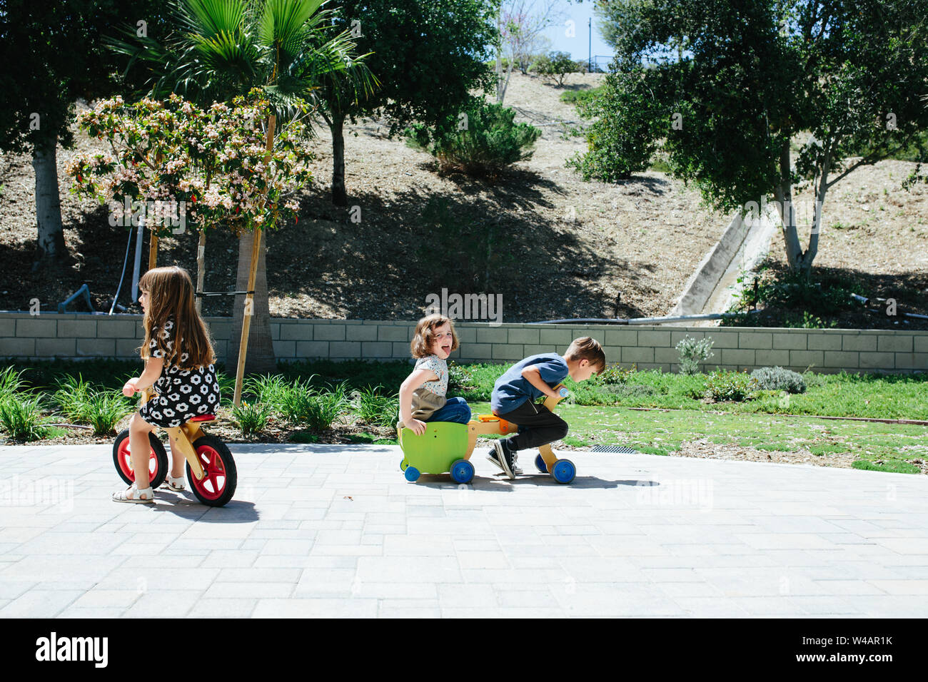 Bambina sorride mentre boy tenta di darle un giro sulla moto push Foto Stock