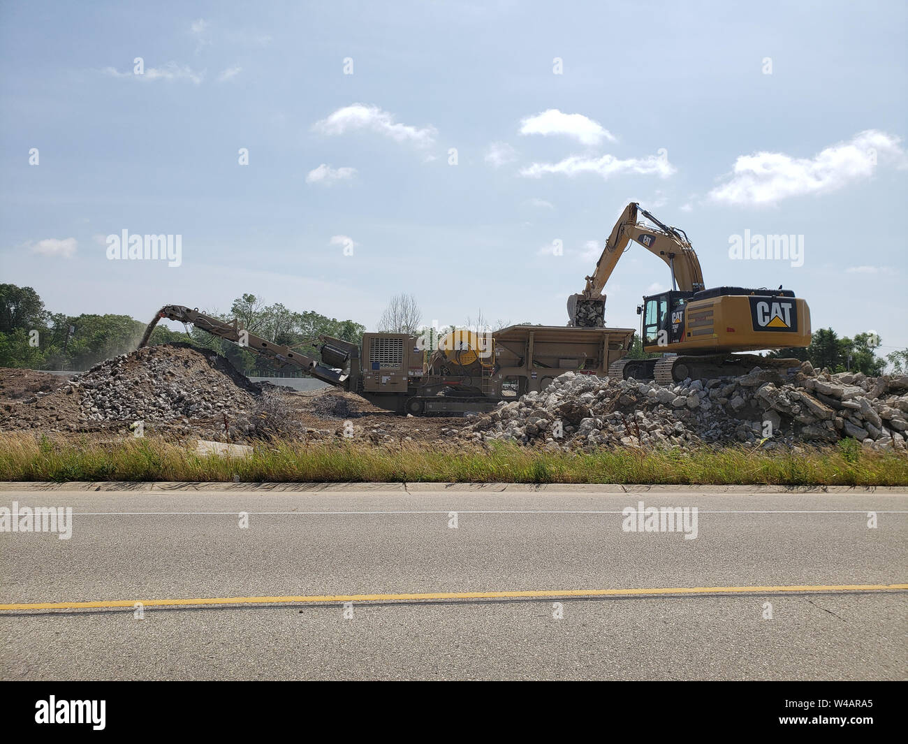 Escavatore caricamento di blocchi di calcestruzzo in una macchina fresatrice per assistere nell'ampliamento della Interstatale 94 a Racine, Wisconsin vicino al nuovo sito Foxconn. Foto Stock