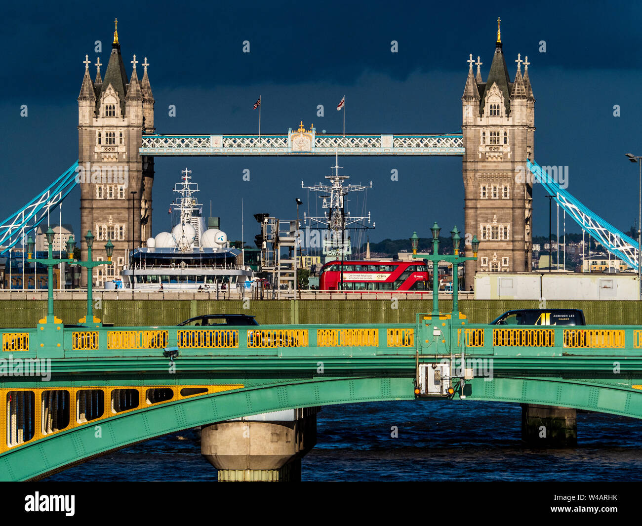 Tower Bridge Londra sotto il cielo tempestoso. L'iconico Tower Bridge contro un cielo scuro con il traffico di Southwark Bridge e London Bridge visibile in primo piano Foto Stock