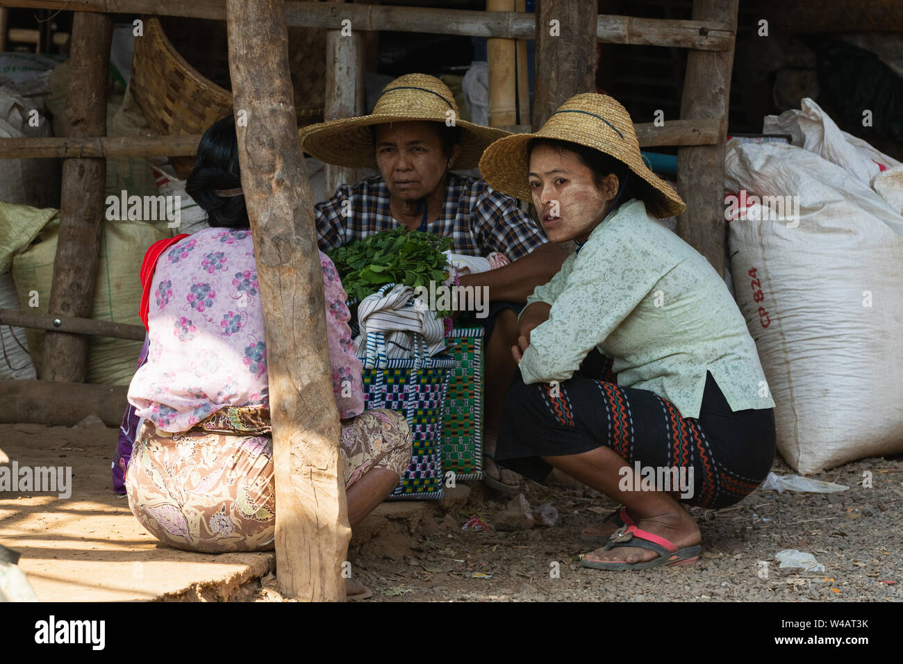 Indein, Myanmar - Marzo 2019: donne birmane in cappelli di paglia avente una chat della strada del mercato sul Lago Inle, Myanmar Foto Stock