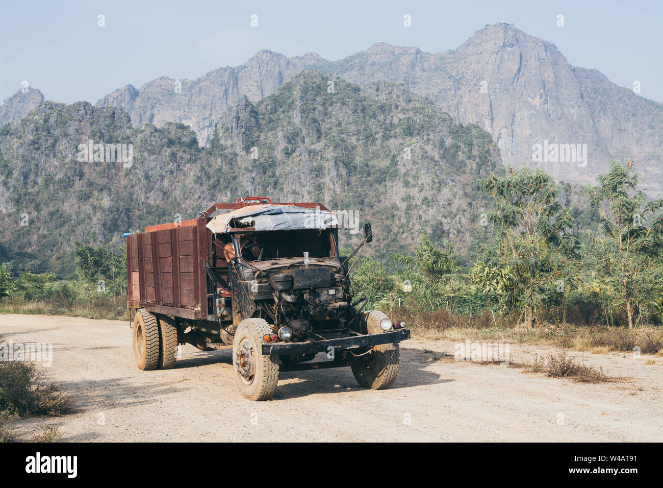 Vecchio carrello di guida su strada sterrata con Zwegabin montagna su sfondo di Hpa-an, Myanmar. Foto Stock