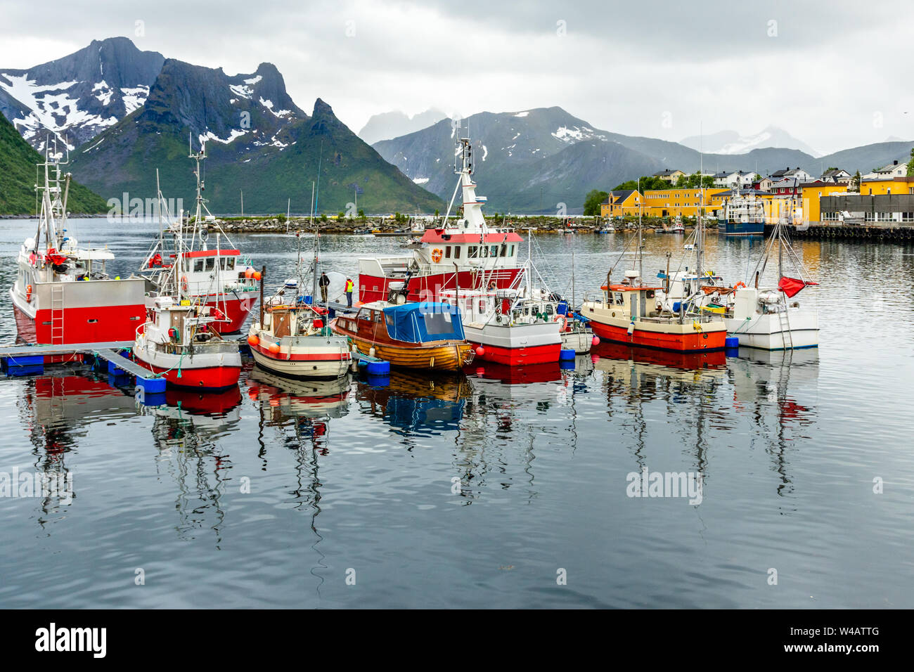 Barche da pesca al molo con la montagna in background a Husoy village, Senja isola, Norvegia Foto Stock