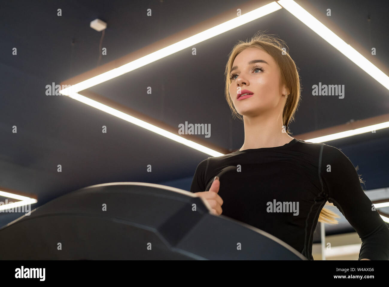 Ritratto di giovane donna di montare sul moderno tapis roulant in palestra Foto Stock