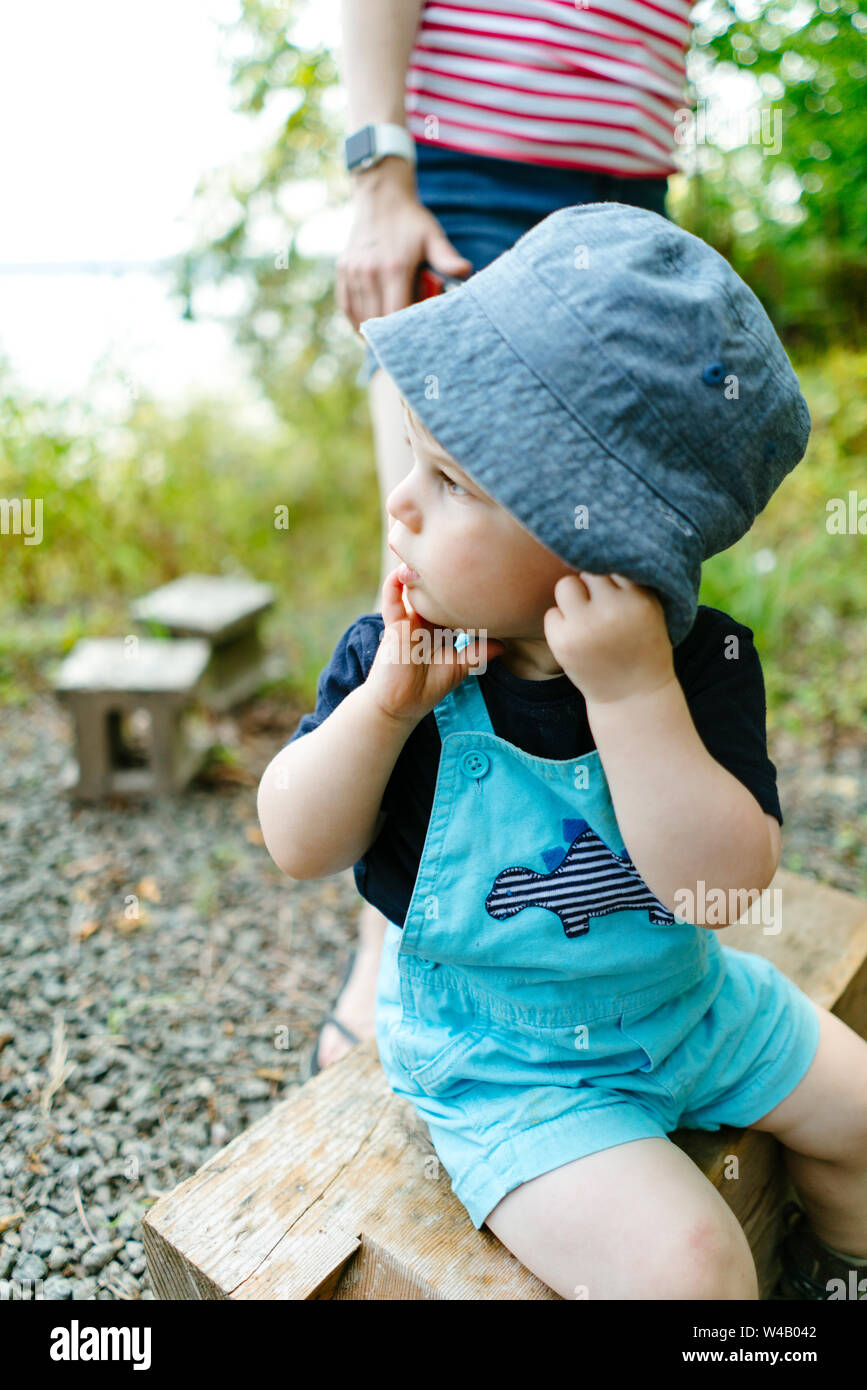 Primo piano vista laterale verticale di un giovane ragazzo in un cappello durante il campeggio Foto Stock