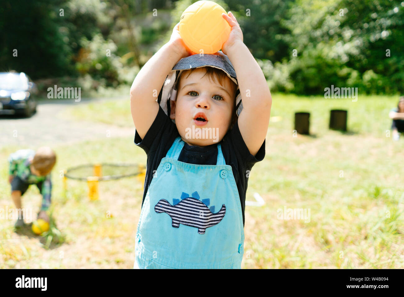 Primo piano ritagliato ritratto di un bimbo piccolo ragazzo giocando con un giocattolo sfera Foto Stock