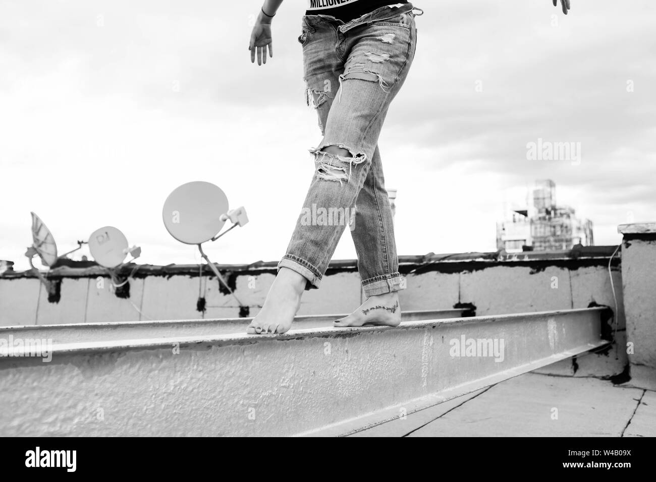 Donna saldi lungo un tetto in jeans strappati Foto Stock