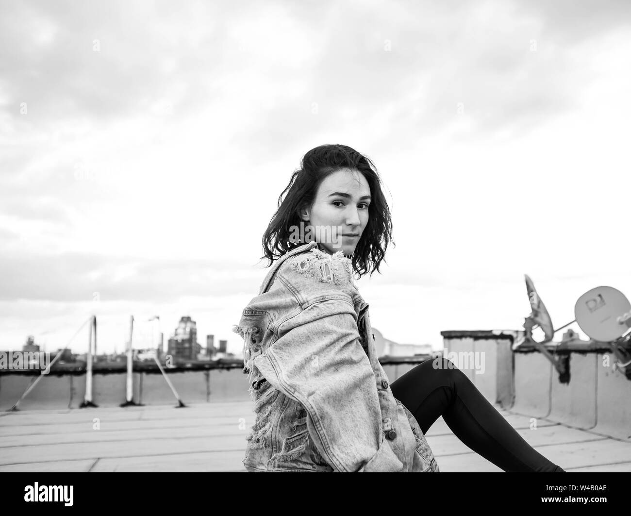 Giovane donna siede sul tetto di Brooklyn Foto Stock