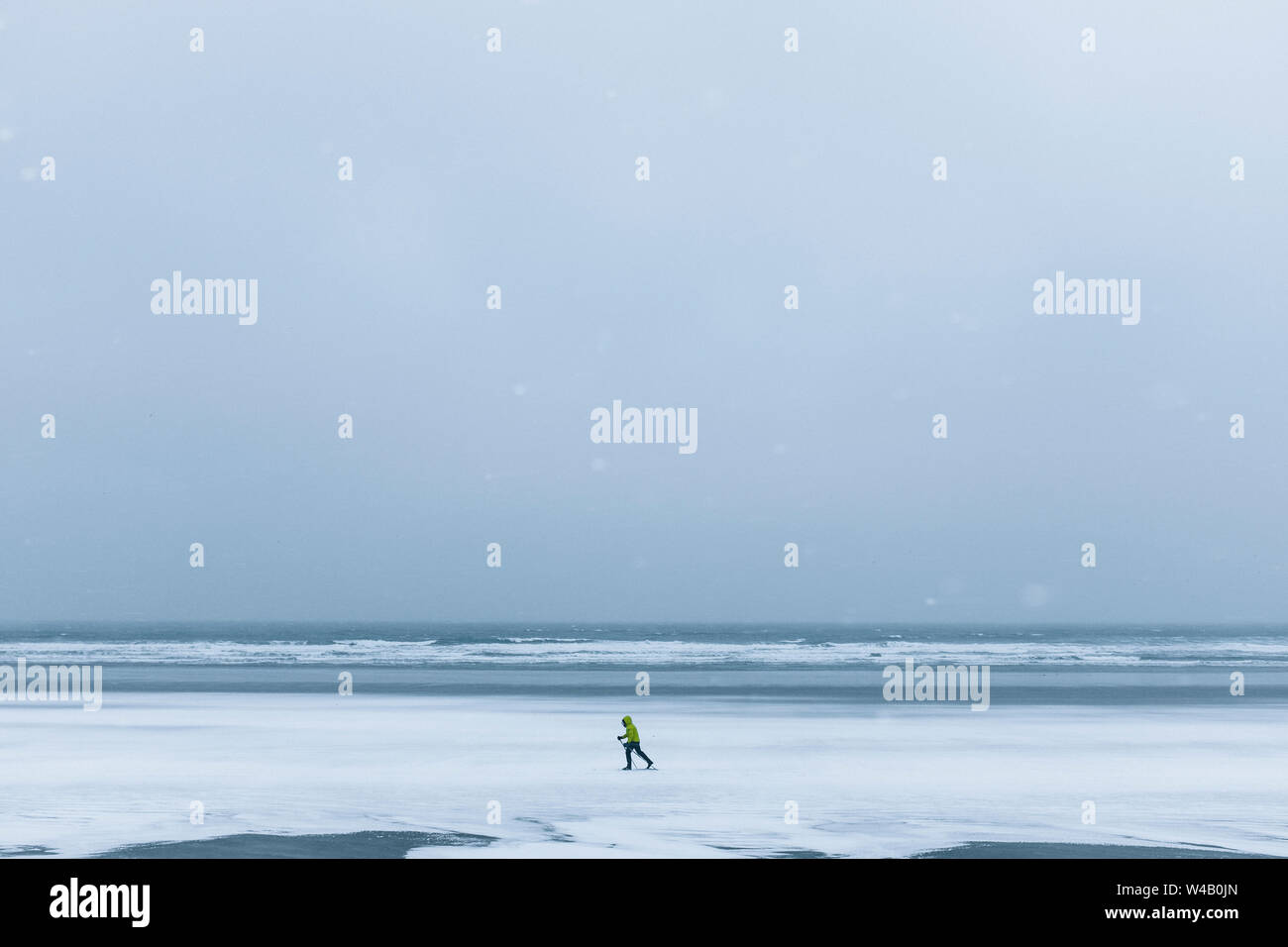 Un solitario sciatore rende il loro modo attraverso una spiaggia congelati in York, Maine Foto Stock