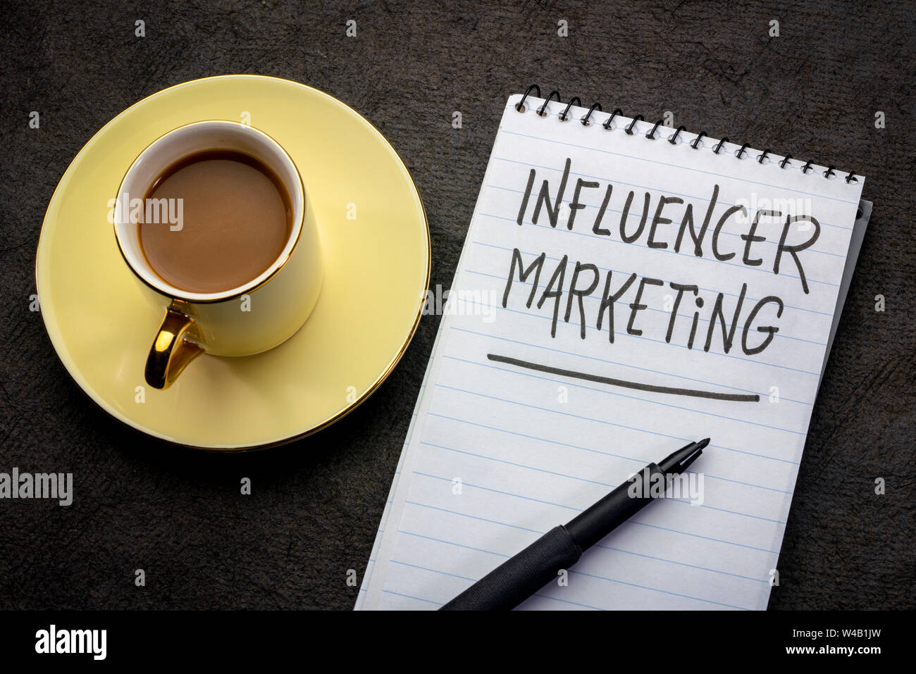 Influencer Marketing - scrittura in un notebook a spirale con una tazza di tè Foto Stock