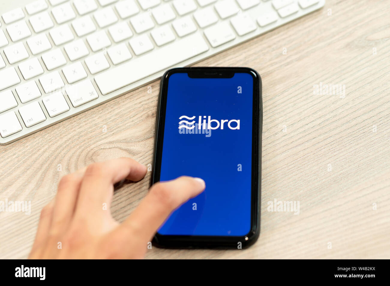 12 luglio 2019, Ljubljana Slovenia - Mano toccando lo smartphone con il logo di Libra su di esso. Facebook è di nuovo cryptocurrency globale per le transazioni Foto Stock