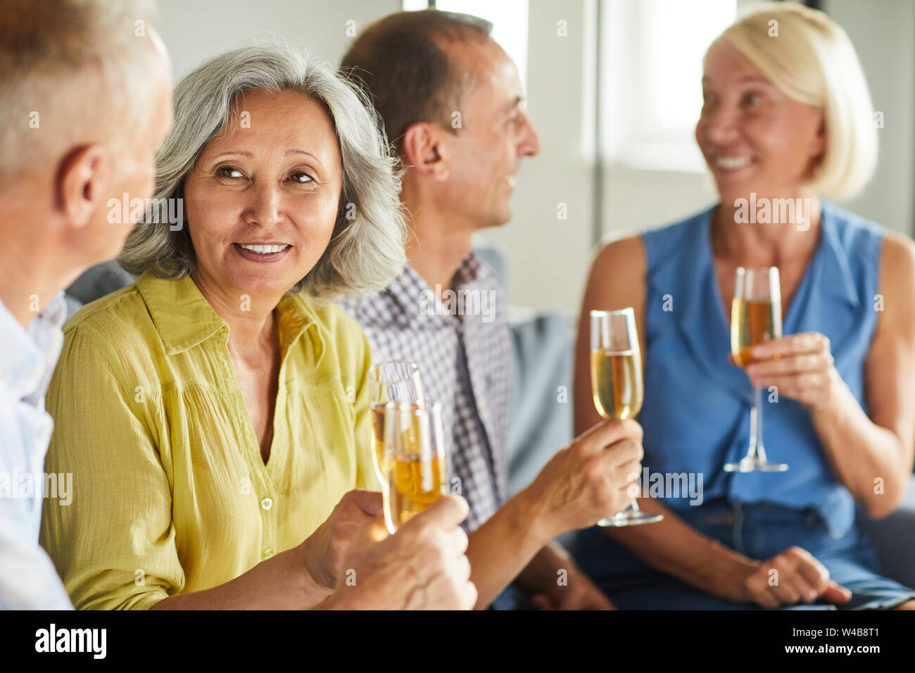 Gruppo di senior moderno persone bere champagne mentre godendo parte a casa, spazio di copia Foto Stock