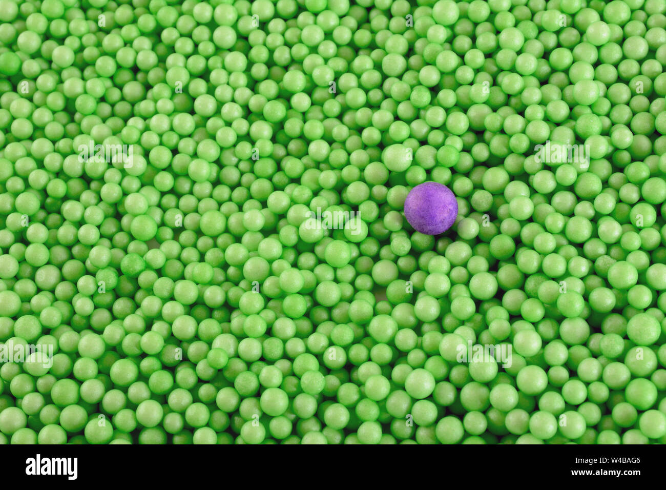 Uno viola la sfera di polistirene in una folla di verde più piccole sfere di polistirene come concetto visivo di differenza Foto Stock