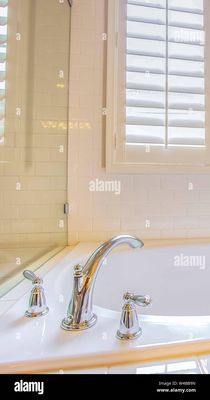 Altezza verticale del telaio interno Bagno con incorporato nella vasca da bagno e la salvietta lucido asta sul muro bianco. La finestra con persiane fornisce illuminazione naturale in Foto Stock