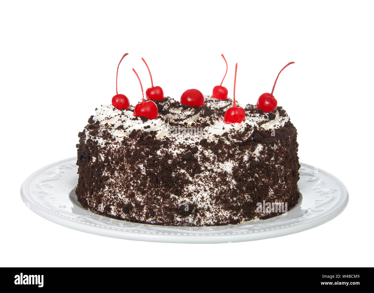 Tutta la torta della Foresta nera su un bianco piastra di porcellana isolato su uno sfondo bianco. Panna montata, briciola di rivestimento di cioccolato, ciliegie sulla parte superiore. Foto Stock