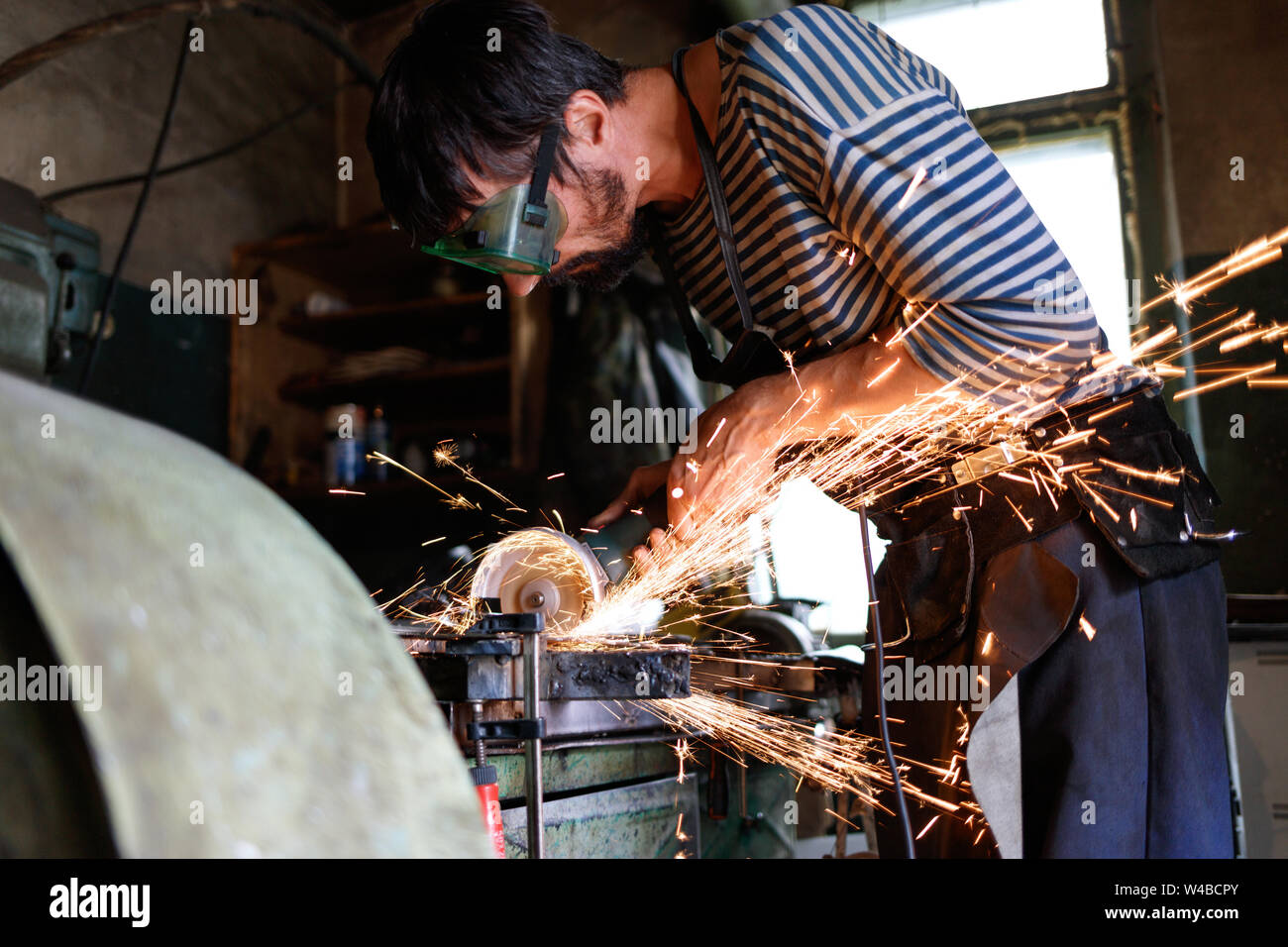 Professional fabbro taglio dei metalli con la mano la sega circolare a forge. Foto Stock