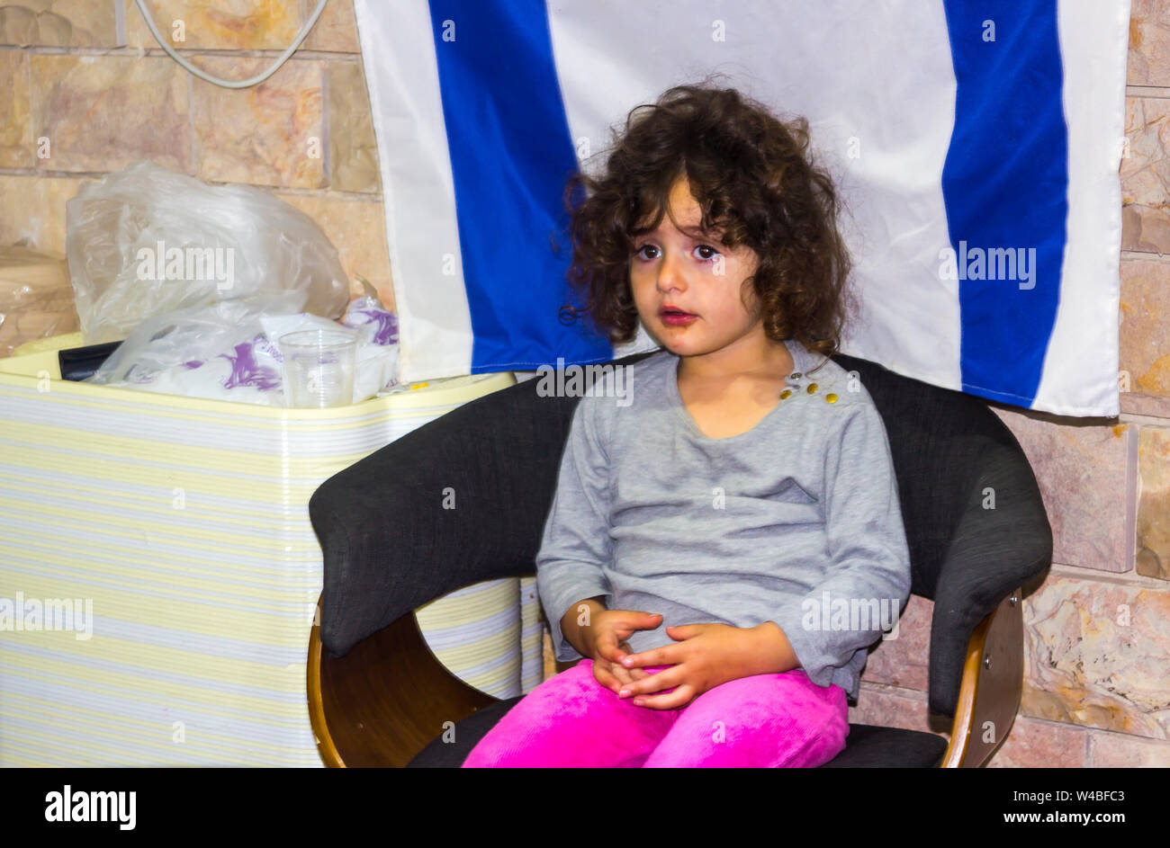 5 maggio 2018 un bel giovane ragazza ebrea si siede tranquillamente nella parte anteriore di una bandiera israeliana come i suoi genitori per assistere i clienti nel loro ristorante a Nazareth Foto Stock