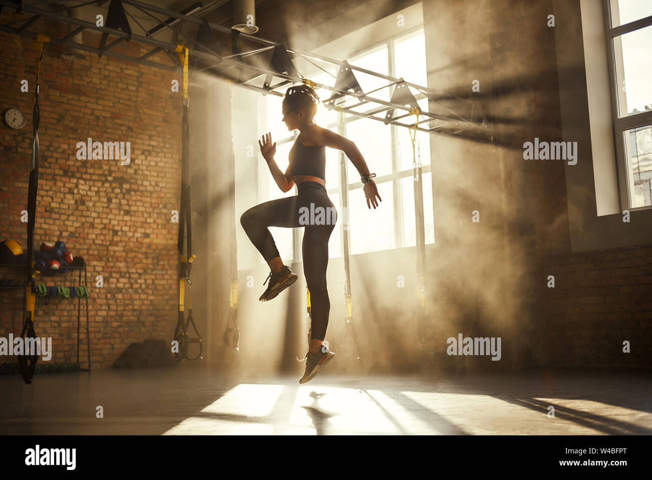 Sempre in buona forma a lunghezza piena di atletica donna in nero sport abbigliamento esercizio in palestra professionale. Lo sport professionistico. TRX Training. Allenamento Foto Stock
