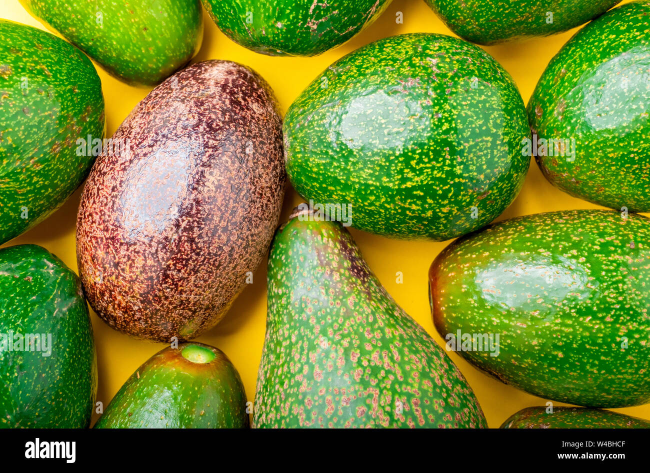 Close up organico rosso di avocado nel gruppo di verde avocado cibo sano su giallo sfondo tabella.moderni organici frutta fresca.farm to table.super foods k Foto Stock