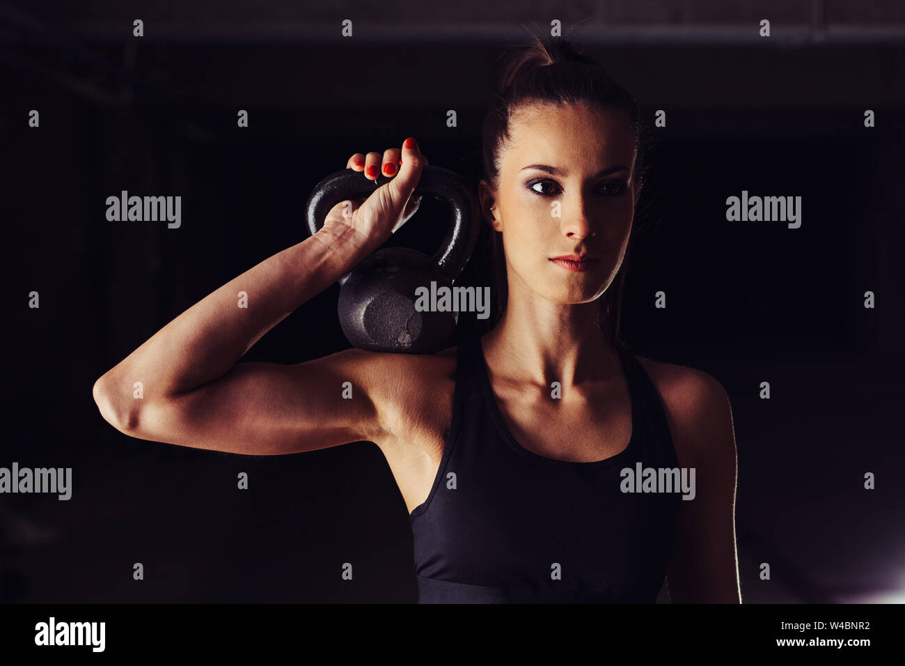 Attraente bodybuilder femminile tonificare il suo braccio durante un allenamento kettlebell Foto Stock