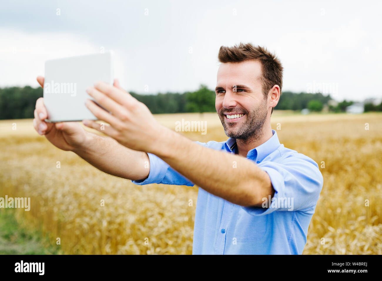 Uomo felice con tavoletta digitale in piedi in campo Foto Stock