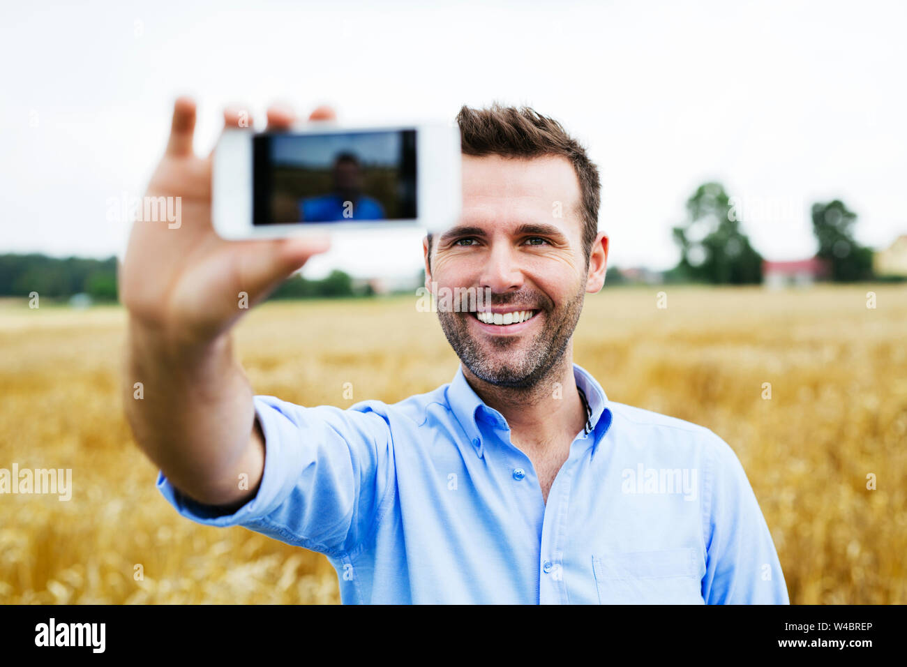 Felice l'uomo prendendo selfie in un campo Foto Stock