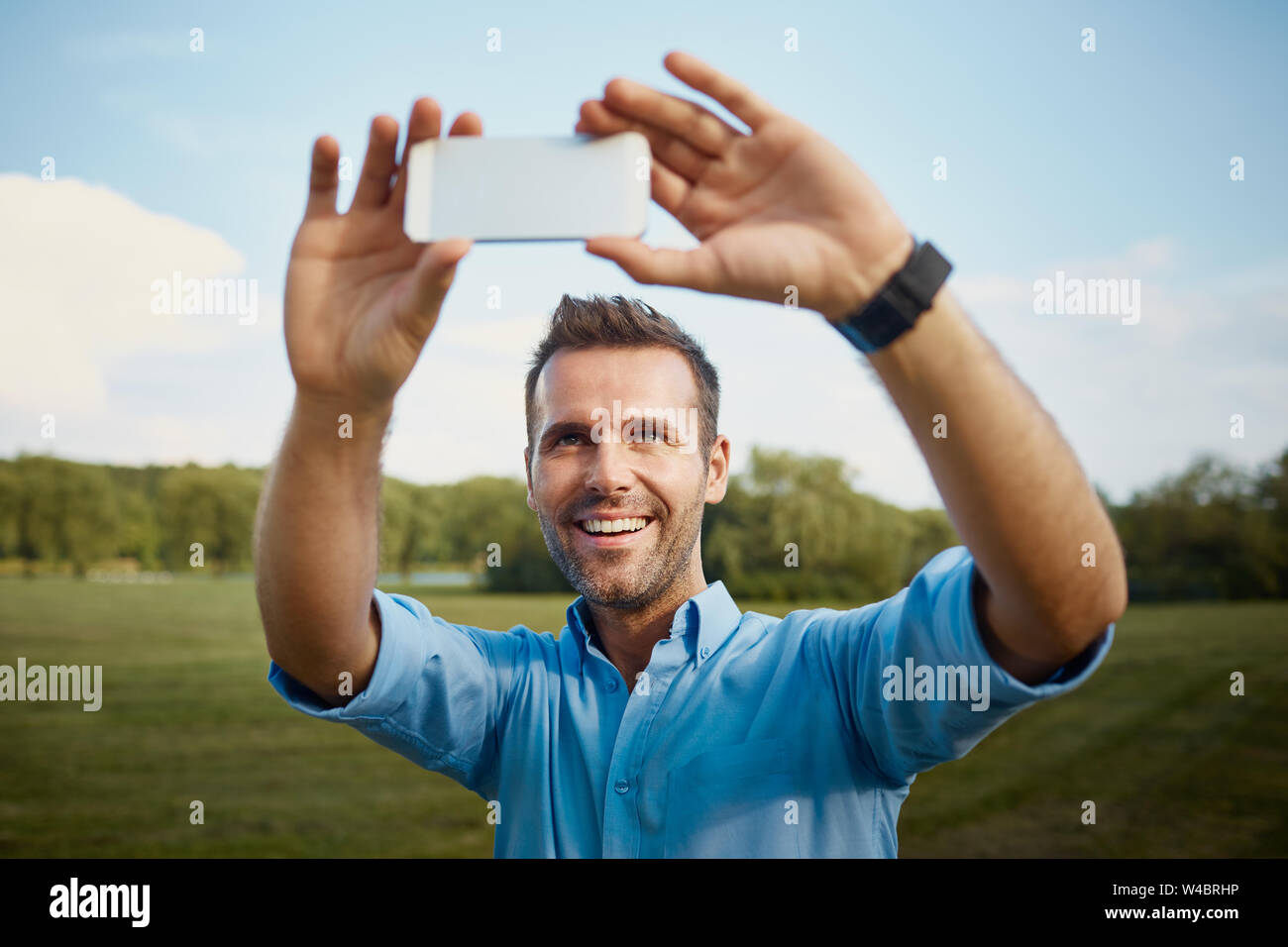 Felice metà uomo adulto prendendo selfie in posizione di parcheggio Foto Stock
