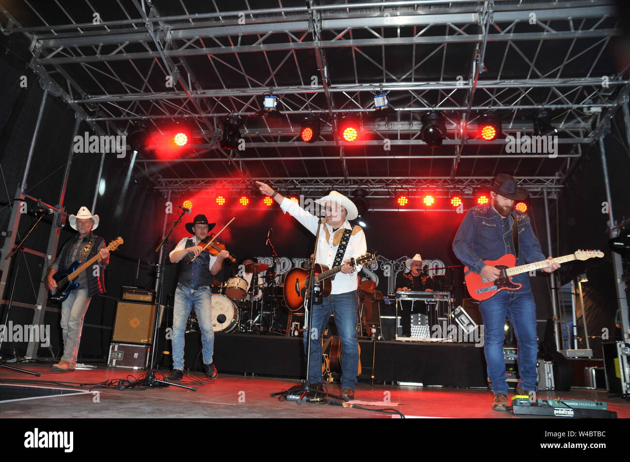 16 luglio 2019, Schleswig-Holstein, Heiligenhafen: arresto carrello - Il paese Band di Waterkant il 16 luglio 2019 in Heiligenhafen al Heiligenhafener Hafenfesttage (per la quarantaquattresima volta dal 11 luglio al 21 luglio 2019) open air fase aspetto dierkt presso il bacino portuale. Da 20 - 22 o'clock vi era Country Rock e canzoni dal nuovo album "Ein Stückchen Ewigkeit' per oltre due mila ospiti dell'evento. Schleswig-Holstein, Germania, Europa. Da sinistra: cappello bianco e grigio shirt - Uwe persa. Black Hat e violino - Tim Reese. Cappello bianco e camicia bianca - Andreas Cisek. Cappello Nero e blu Foto Stock