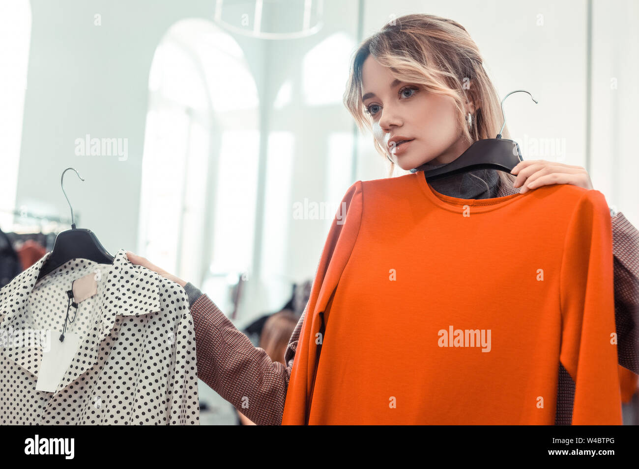 Biondo e sentimento donna premurosa mentre la scelta di vestire Foto Stock